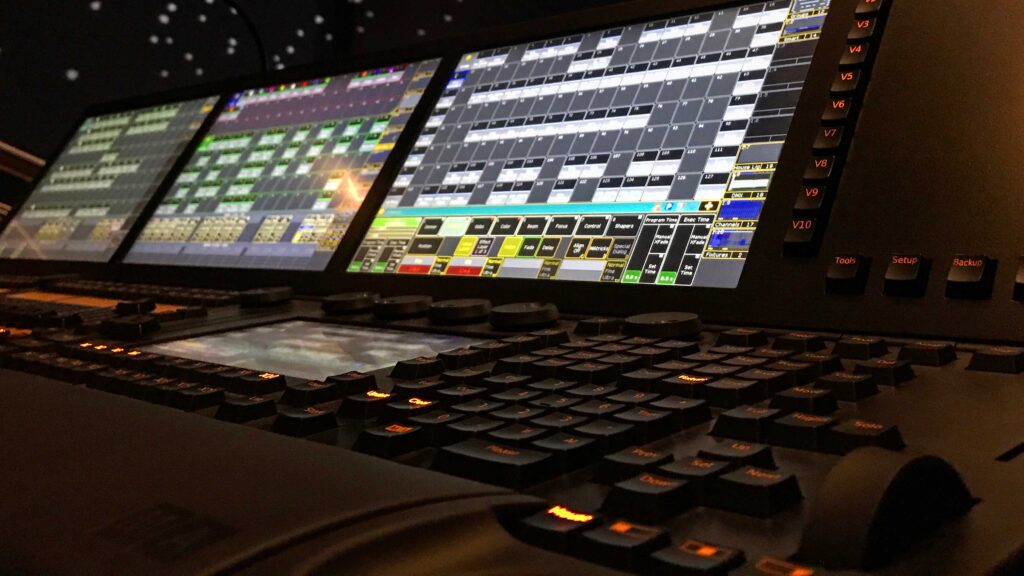 Angle view of a digital lighting console showing control buttons and multicolored screen interface.
